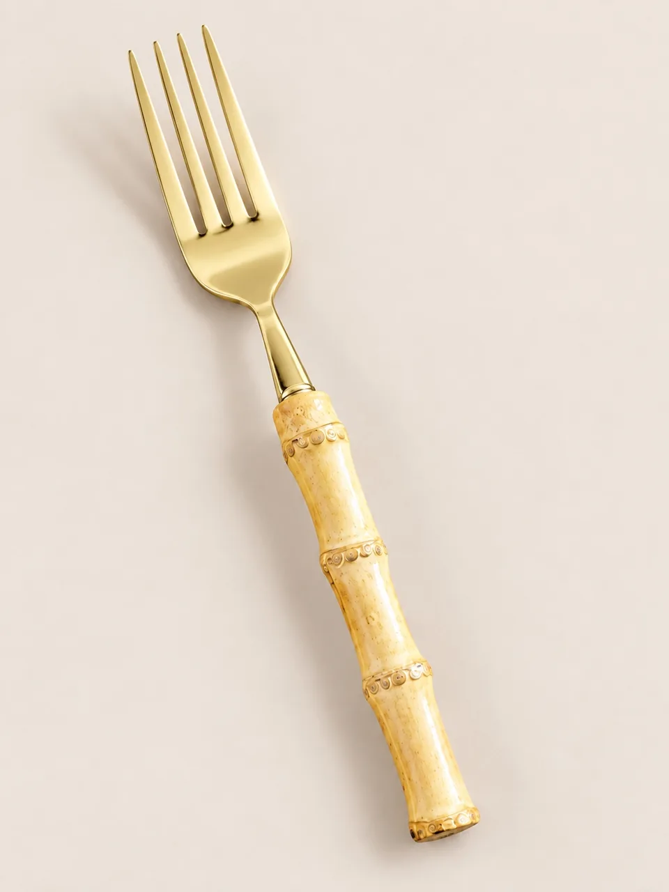 Tenedor de acero dorado con mango de bambú natural, en detalle