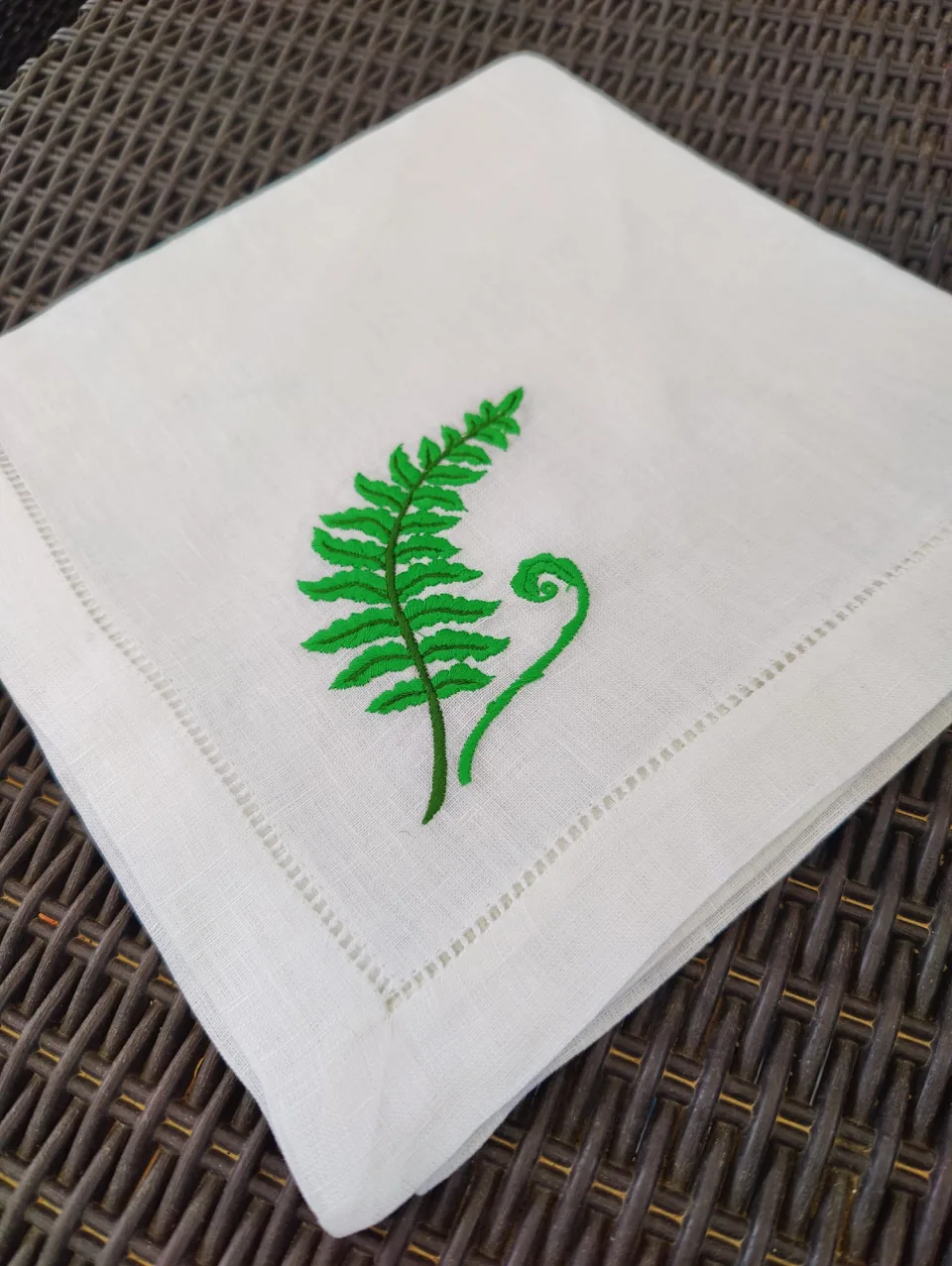 Detalle del bordado de helecho verde en la esquina de la servilleta, junto a la vainica